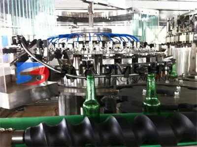 Green glass beer bottles entering a rotary filling machine